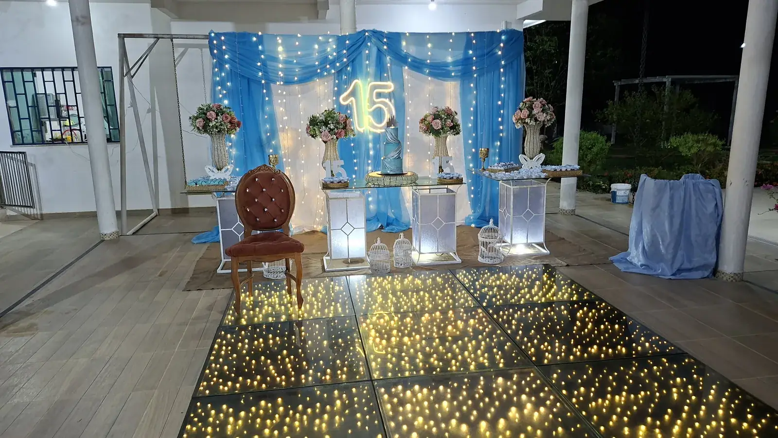Decoração de 15 anos com cortina azul e pista iluminada