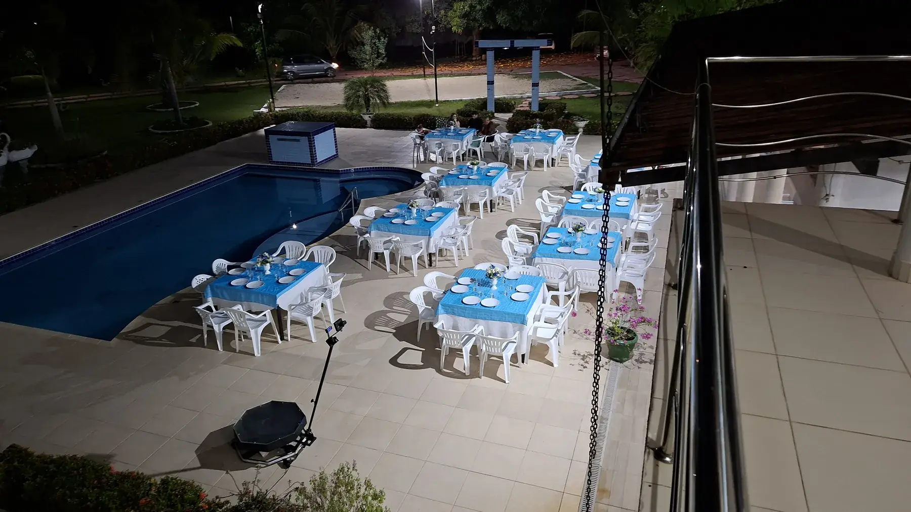 Mesas montadas em volta da piscina, à noite